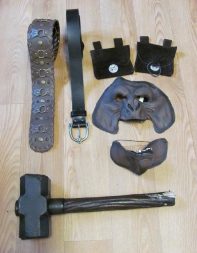 Brede bruine leren riem met metalen studs, neutrale zwarte leren riem, twee bruine suède riemtasjes, latex masker, latex hamer (uiteinde is beschadigd, moet opnieuw gelatext worden)